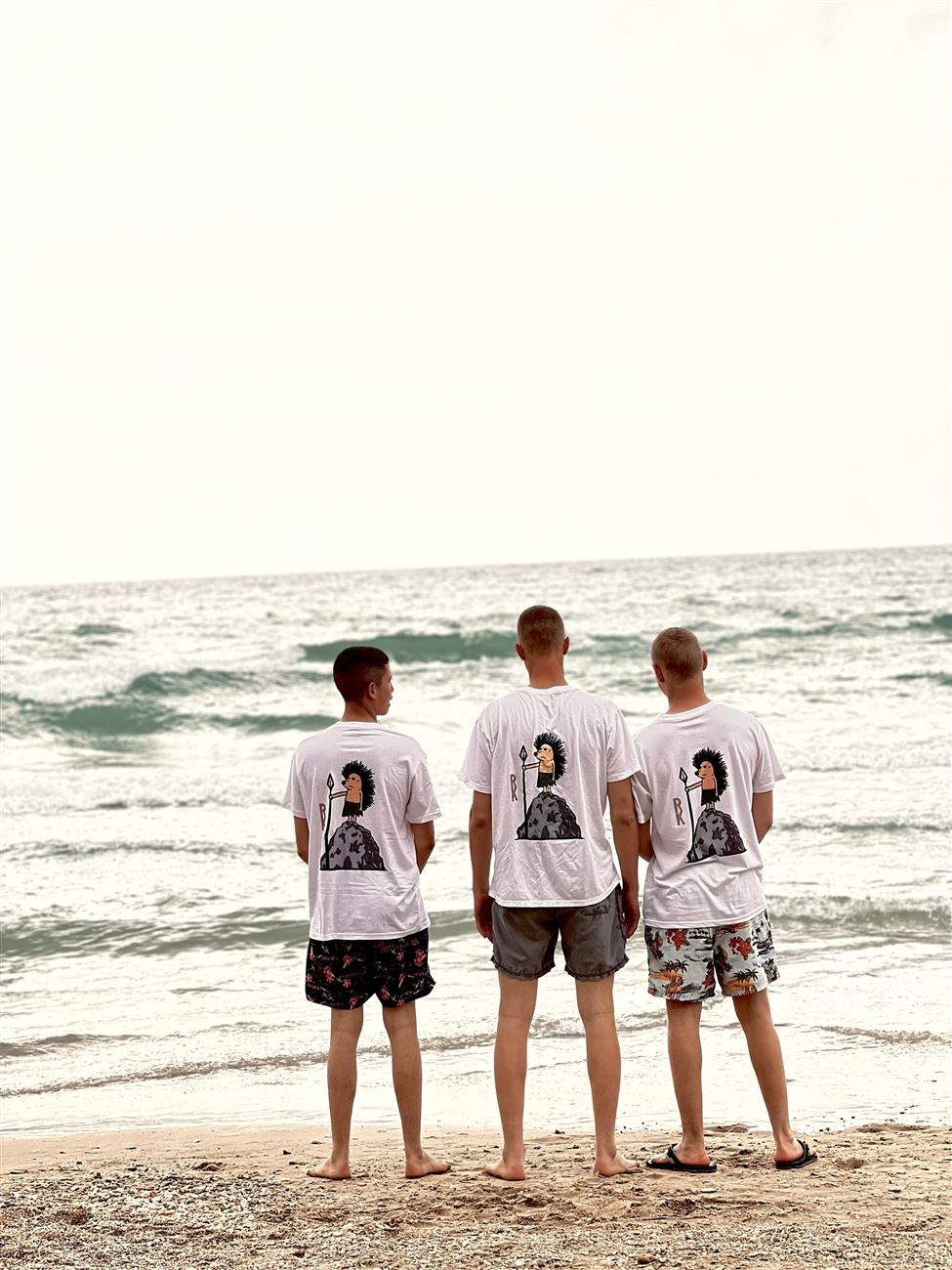 Three friends in Hedgehog tees facing the sea